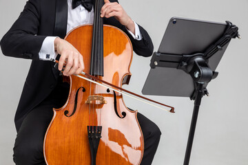 Unrecognizable man artist wearing tuxedo playing cello with music note