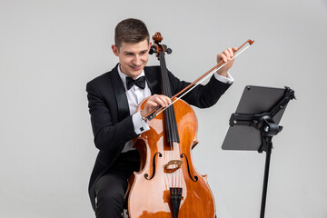 Man artist wearing tuxedo playing cello with music note