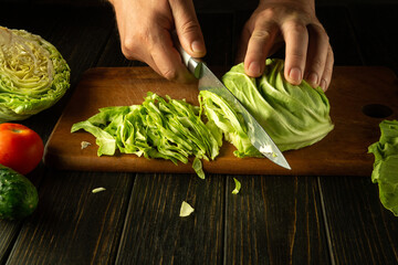 Cutting cabbage for preparing vegetable salad. The chef hands use a knife to chop fresh cabbage on...