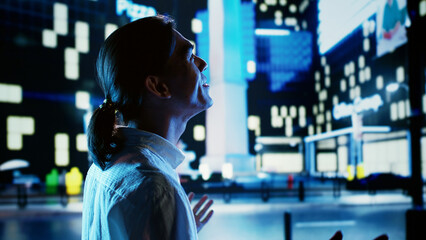 Excited asian man wandering around city avenues during nighttime, exulting from joy, looking upwards to surrounding buildings. Businessman taking a walk, happy about promotion at work