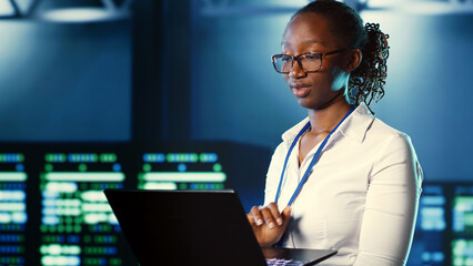 Woman walking through high tech facility server rows providing computing resources for different...