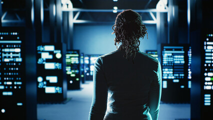 Employee walking through data center infrastructure clusters providing processing resources for...