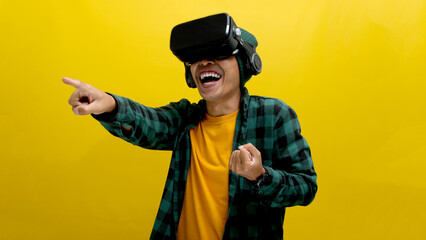 Young Asian man wearing a VR headset points his finger forward, interacting with a virtual reality...