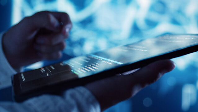 Close up shot of programming scripts on tablet, employing AI machine learning infrastructure. Trained professional manipulating lines of code for artificial intelligence applications development