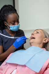 Dark-skinned female dentist working with the patient