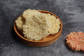 Rengginang is a typical Indonesian snack made from glutinous rice grains that are seasoned and fried. Served on a wooden table on black background. Indonesian food. Camilan gurih