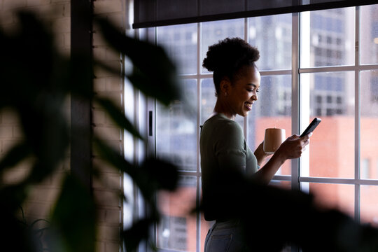 At office, African American businesswoman holding smartphone, looking at screen