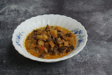 Sambal Goreng Ati Kentang, javanese (Indonesia) traditional food. Served in white bowl. Copy space. black background