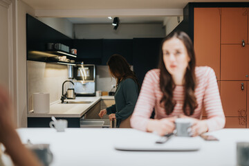 Casual lifestyle scene with two women in a modern kitchen sharing a relaxed moment.