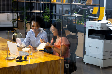 Diverse female colleagues in smart casual attire discussing work late at office
