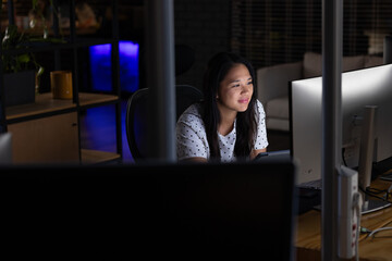 At office, biracial businesswoman studying screen, working late