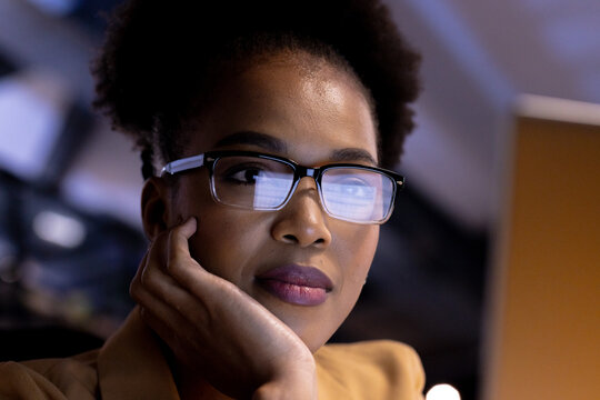African American businesswoman in glasses working late, staring at computer screen