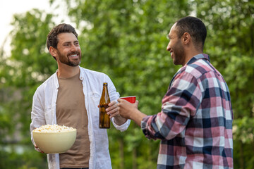 Joyful men friends with beer and popcorn enjoying outdoor party