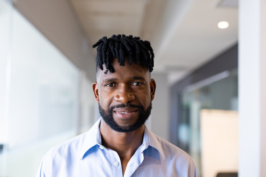 A middle-aged African American man standing at office, wearing blue shirt