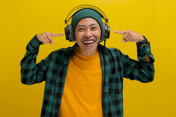 Excited Asian man, wearing headphones and clearly enjoying music, enthusiastically gestures towards...