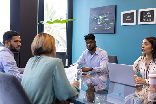 Diverse team discussing at office, biracial woman holding framed quote