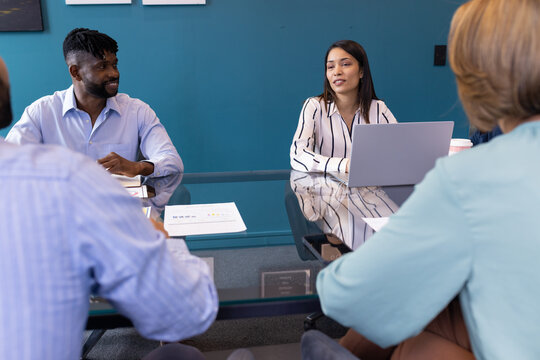 Diverse team discussing business at office, framed quotes on table