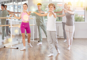 In dance studio, teen boy in group lesson with students rehearses, practices ballet dance, staging.