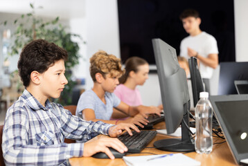 Curious underage boy engaged in IT training during computer courses for children