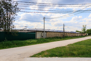 Rural area with a dirt road and a fence, solar panels on the roof