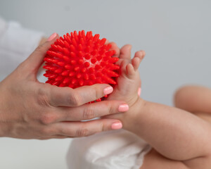 A doctor massages a baby's foot using a spiked ball.