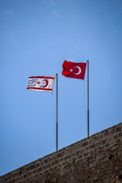 Turkey and Turkish Republic of Northern Cyprus flags waving in the blue and cloudy sky