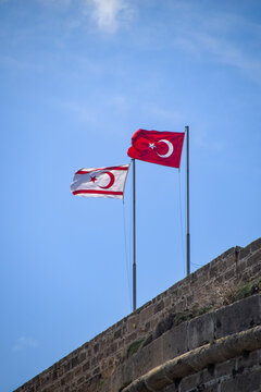 Turkey and Turkish Republic of Northern Cyprus flags waving in the blue and cloudy sky