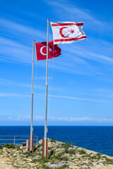 Turkey and Turkish Republic of Northern Cyprus flags waving in the blue and cloudy sky