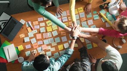 Top down view of designer standing at meeting with sticky note and putting hand together. Aerial...