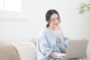 Woman using a computer sitting in the living room Image of a woman working remotely or at home...