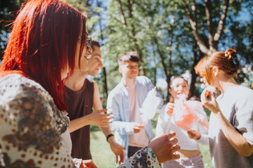 A group of cheerful friends enjoys fluffy cotton candy in a park, experiencing fun and laughter on a sunny day.