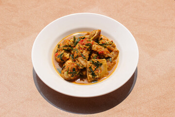 Ayam Rica Rica. Traditional dish from Manado, Indonesia, boiled chicken with the addition of tofu and using spicy spices and garnish served on a white plate