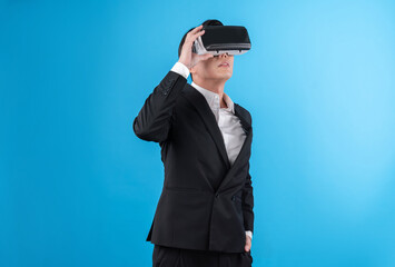Smiling Asian businessman looking thorough VR connecting to business world report in futuristic...