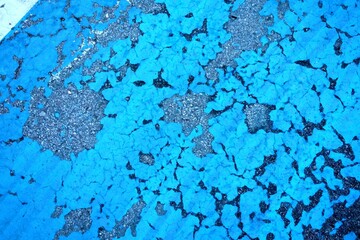 Blue peeling paint on asphalt road