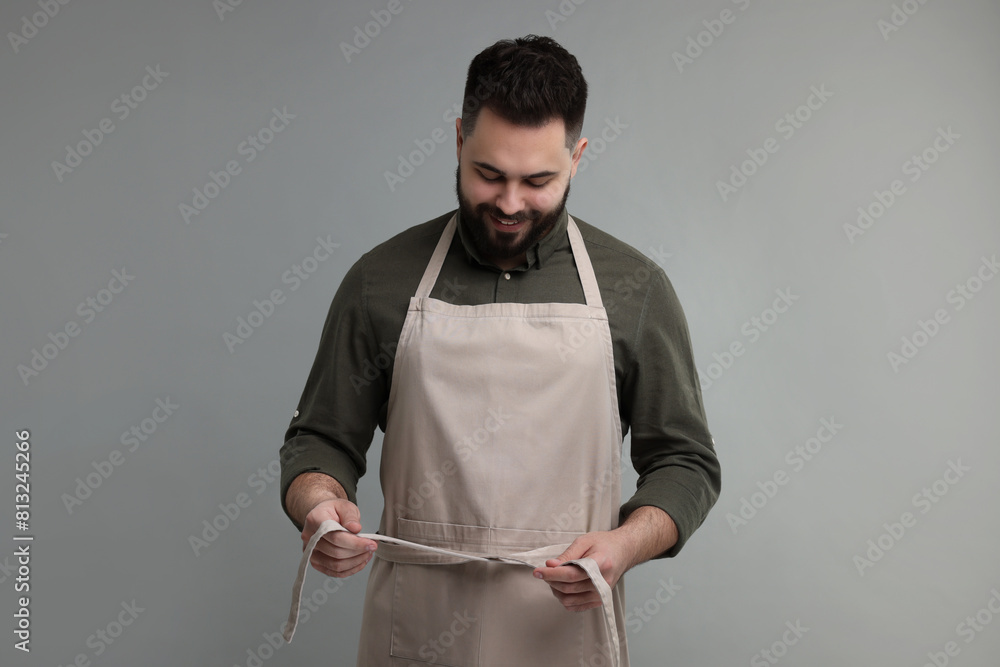 Canvas Prints Smiling man in kitchen apron on grey background. Mockup for design