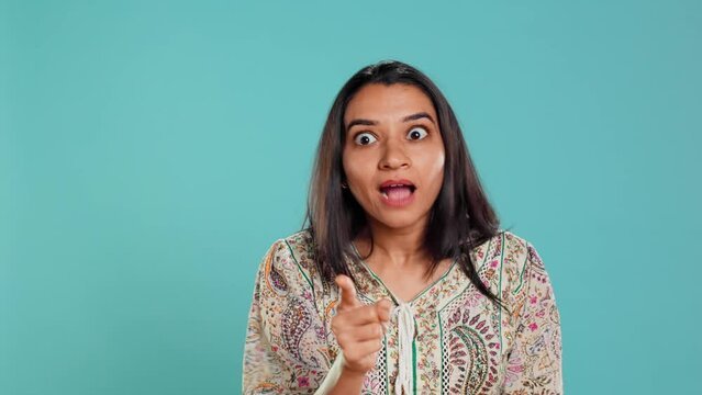 Upset indian person fighting with friend, doing scolding gesturing, isolated over studio backdrop. Annoyed woman arguing with opponent during discussion, doing admonishing hand gestures, camera B