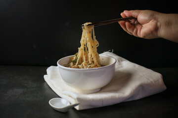 Noodle with Kao Lao Moo Toon. Thai pork stew soup in white bowl on black table. Street food in Thailand.