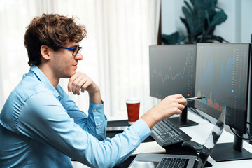 Working young business trader looking on laptop on laptop and pc in market stock graph investing in real time screens at modern home office, analyzing dynamic exchange rate investment concept. Gusher.