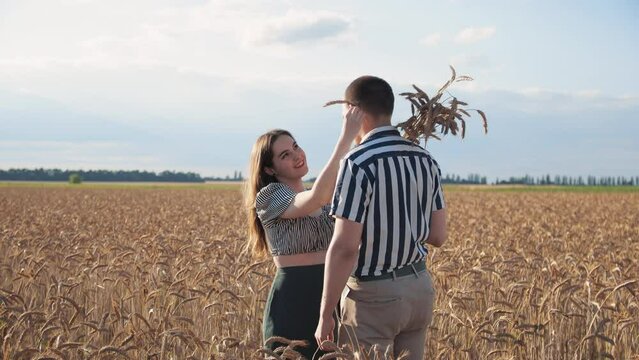 Man and woman on a date in the field. They stand, caress. Golden hour, sunset. Summer