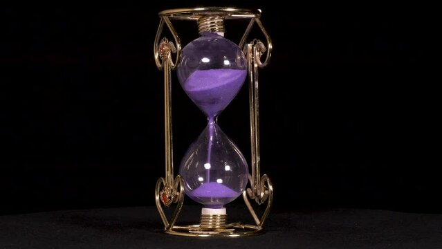 Close-up footage of hourglass on black background.