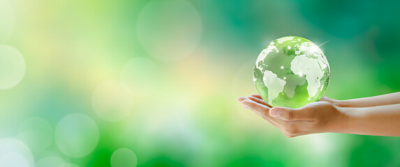 Globe crystal glass ball in hands. Green Sunny background with bokeh. World mental health and World earth day. Saving environment and World Ecology Concept.
