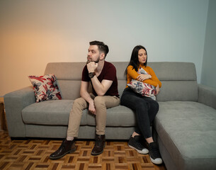 Young heterosexual couple in a fight sitting opposite to each other on couch 