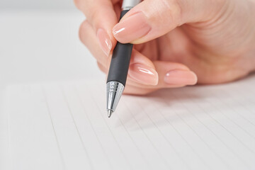 ペンを持ってノートに書く女性の手元