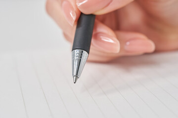 ペンを持ってノートに書く女性の手元