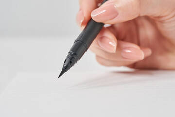 筆ペンを持つ女性の手元
