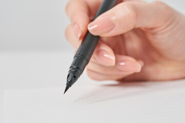 筆ペンを持つ女性の手元