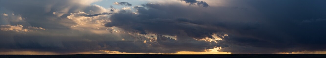 Landscape at sunset. A thunderstorm is approaching the village. Tragic gloomy sky. Panorama.