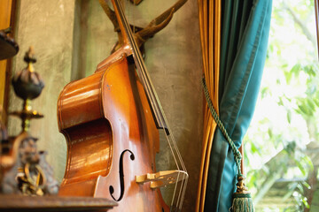 The violin was placed near the window with curtains.