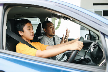 Potrait Of Son Driving Car While Holding Steer And Shocked Father Tell To Stop. Father Teaching Son To Learning Drive Car. 