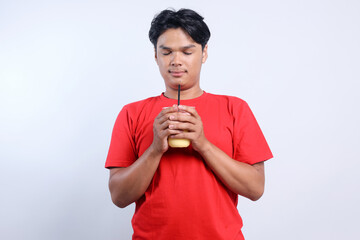Potrait Of Relaxed Asian Young Male Holding Juice Drink Isolated On White Background